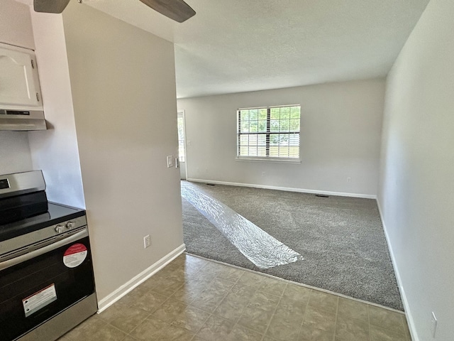 kitchen featuring white cabinets, light colored carpet, ceiling fan, a textured ceiling, and stainless steel range oven