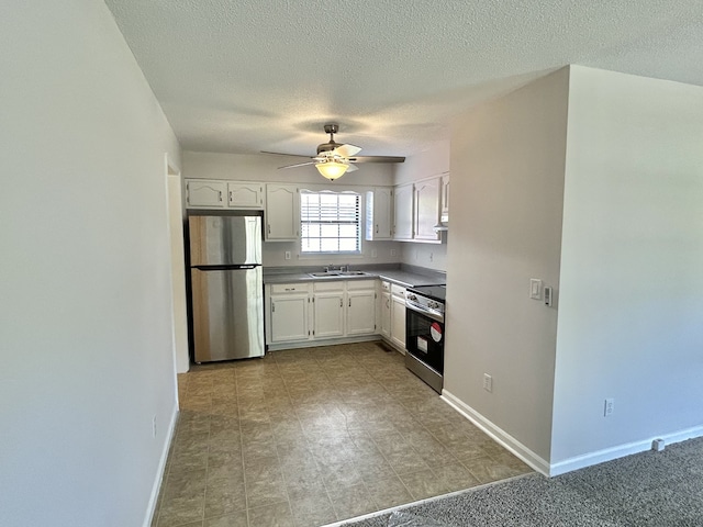 kitchen with appliances with stainless steel finishes, a textured ceiling, ceiling fan, sink, and white cabinets