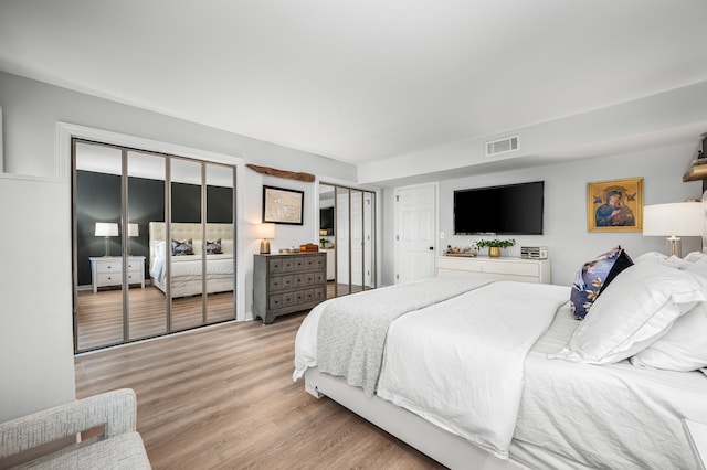 bedroom with light wood-type flooring and two closets