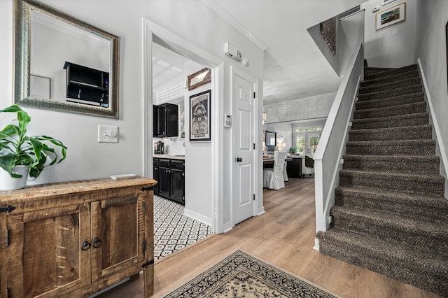 stairs featuring hardwood / wood-style floors and ornamental molding