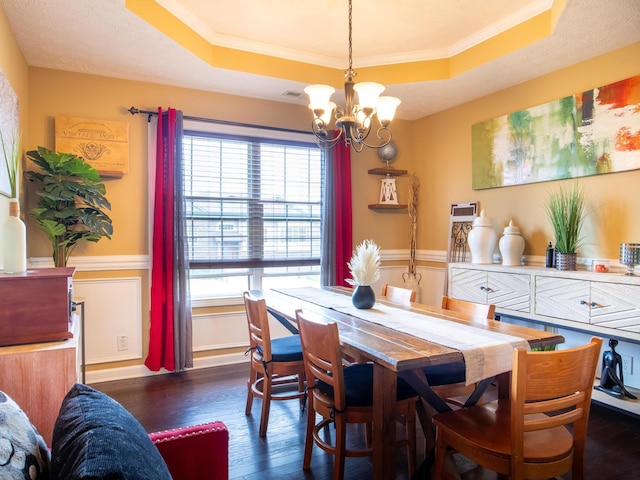 dining space featuring a tray ceiling, crown molding, dark wood-type flooring, and an inviting chandelier