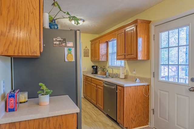 kitchen with stainless steel dishwasher, a healthy amount of sunlight, sink, and a textured ceiling