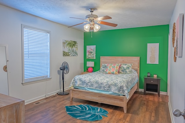 bedroom featuring ceiling fan, dark hardwood / wood-style flooring, and a textured ceiling