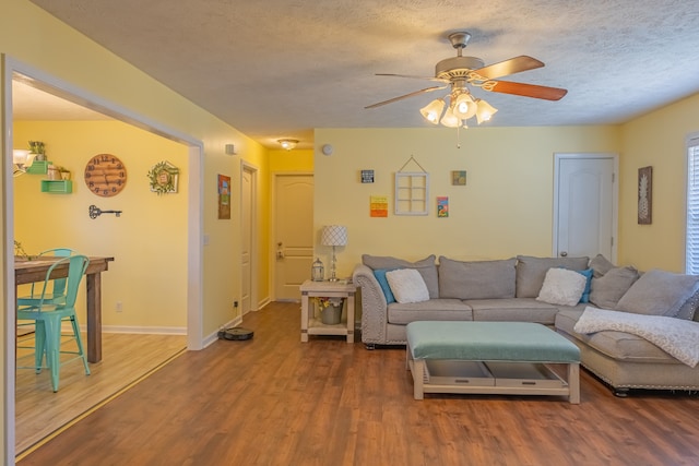 living room with hardwood / wood-style floors, ceiling fan, and a textured ceiling