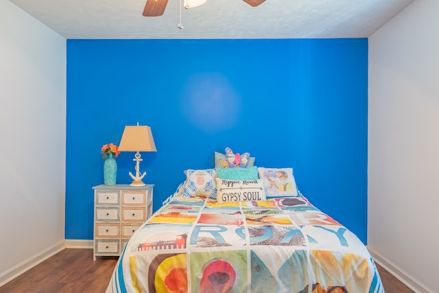 bedroom with a textured ceiling, ceiling fan, and dark wood-type flooring