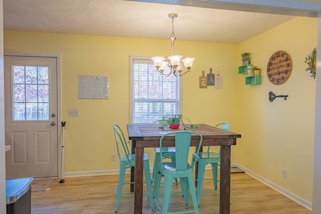 dining space featuring light wood-type flooring, a wealth of natural light, and a chandelier