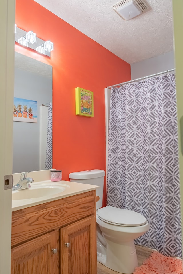 bathroom with vanity, a textured ceiling, toilet, and curtained shower