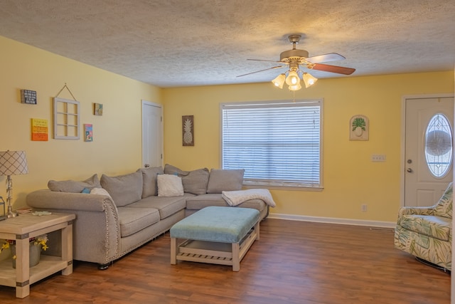 living room with ceiling fan, plenty of natural light, dark wood-type flooring, and a textured ceiling