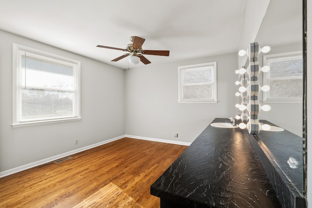 unfurnished room featuring hardwood / wood-style flooring, ceiling fan, a healthy amount of sunlight, and sink