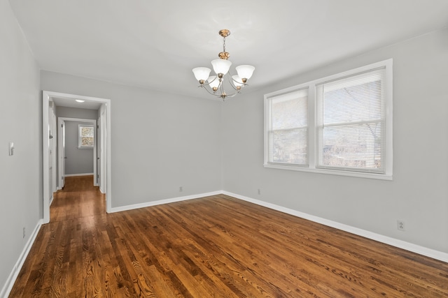 unfurnished room featuring dark wood-type flooring and an inviting chandelier