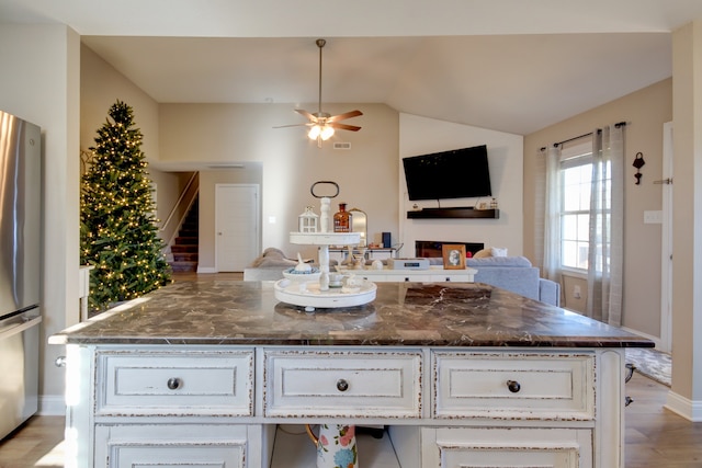 kitchen featuring a center island, lofted ceiling, white cabinets, light wood-type flooring, and stainless steel refrigerator