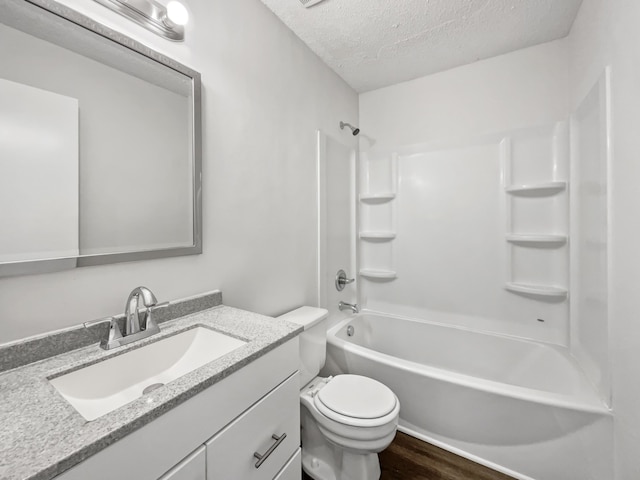 full bathroom with washtub / shower combination, wood-type flooring, a textured ceiling, toilet, and vanity