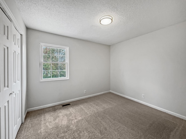 carpeted spare room with a textured ceiling