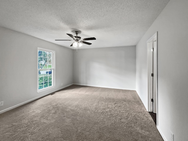 empty room with ceiling fan, dark carpet, and a textured ceiling