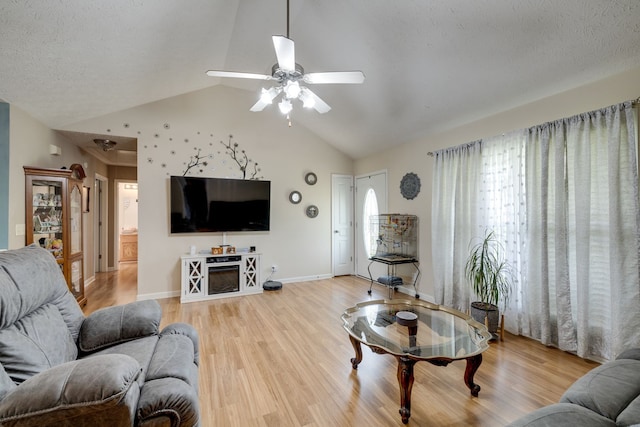 living room with lofted ceiling, ceiling fan, light hardwood / wood-style floors, and a textured ceiling