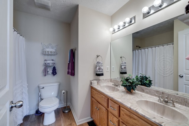 bathroom with vanity, hardwood / wood-style floors, toilet, and a textured ceiling