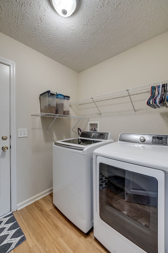 laundry area featuring separate washer and dryer, a textured ceiling, and light wood-type flooring