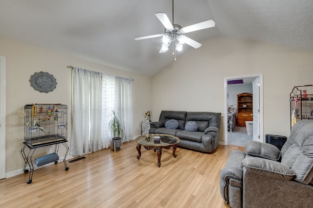 living room with lofted ceiling, ceiling fan, and light hardwood / wood-style flooring