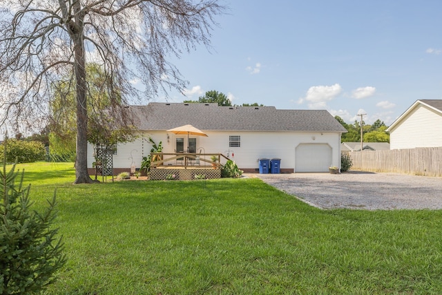 rear view of house with a wooden deck, a garage, and a lawn