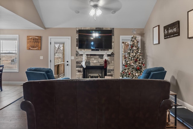 living room featuring lofted ceiling, plenty of natural light, hardwood / wood-style floors, and a stone fireplace