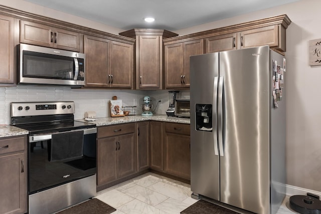 kitchen with dark brown cabinetry, appliances with stainless steel finishes, light stone countertops, and backsplash