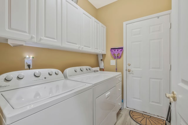 laundry room featuring light hardwood / wood-style floors, cabinets, and washing machine and clothes dryer