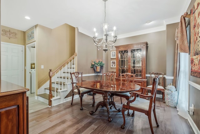 dining room featuring ornamental molding, light wood-type flooring, and a notable chandelier