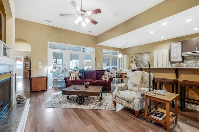 living room with ceiling fan, a fireplace, and dark wood-type flooring