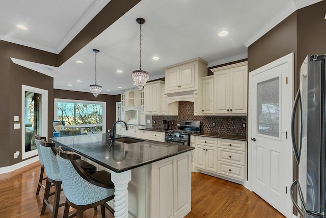 kitchen with sink, wood-type flooring, pendant lighting, a kitchen island with sink, and appliances with stainless steel finishes