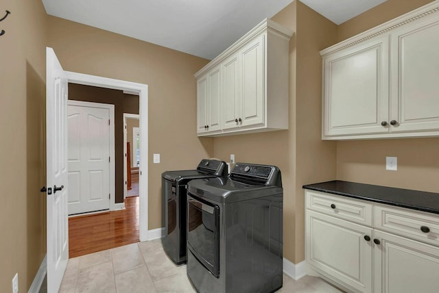 clothes washing area with light hardwood / wood-style floors, cabinets, and washing machine and clothes dryer