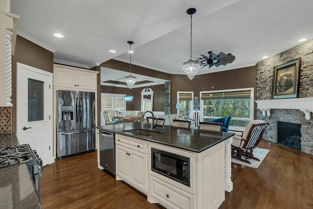 kitchen with dark wood-type flooring, sink, black appliances, pendant lighting, and a fireplace