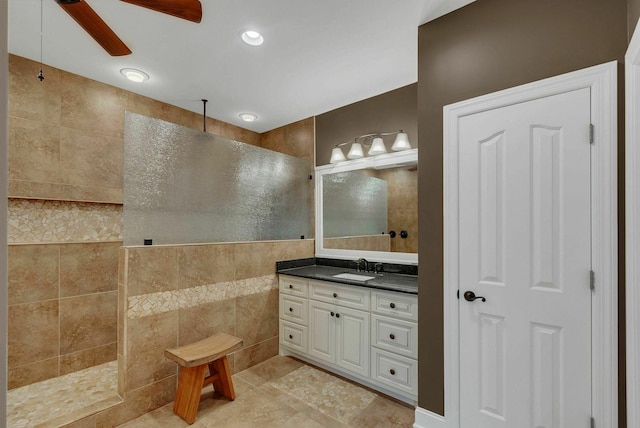 bathroom featuring vanity, ceiling fan, a shower, tile walls, and tile patterned flooring