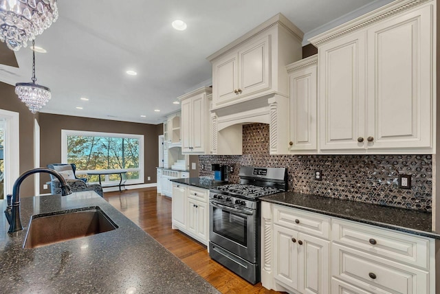 kitchen with pendant lighting, hardwood / wood-style floors, sink, gas range, and a notable chandelier