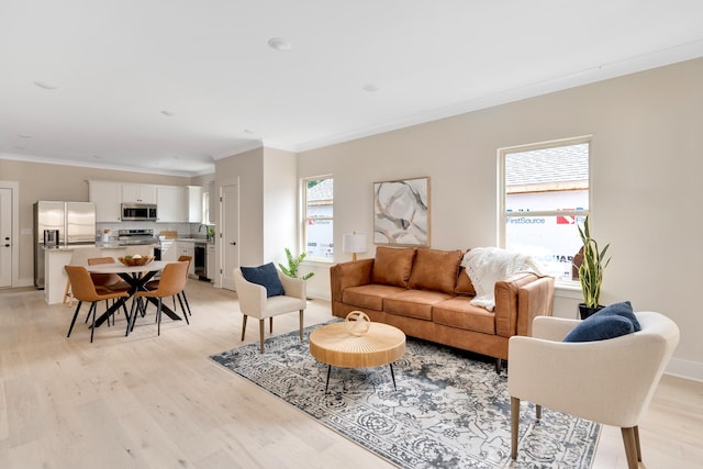 living room featuring light hardwood / wood-style floors, a wealth of natural light, and ornamental molding