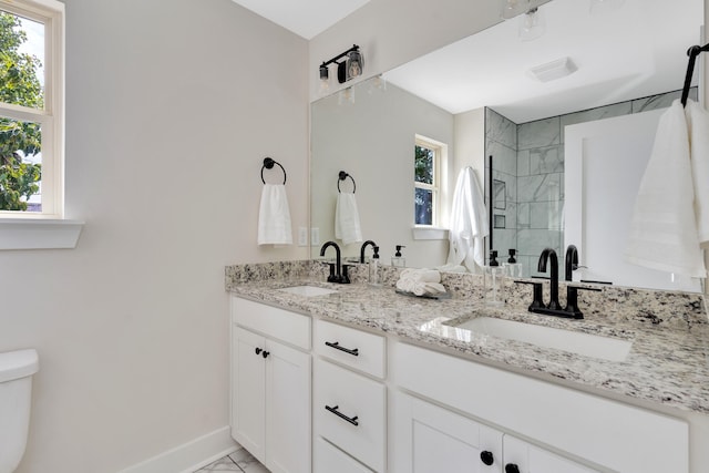 bathroom featuring a tile shower, vanity, and toilet