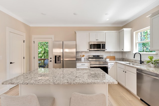 kitchen with a breakfast bar, a healthy amount of sunlight, sink, and appliances with stainless steel finishes