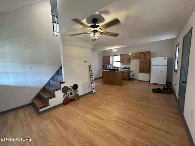 kitchen featuring ceiling fan, white fridge, light hardwood / wood-style floors, a textured ceiling, and a kitchen island