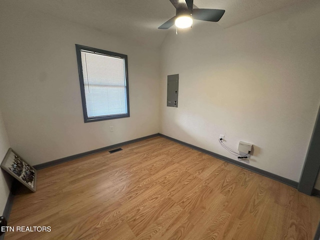 empty room featuring ceiling fan, light hardwood / wood-style floors, lofted ceiling, and electric panel