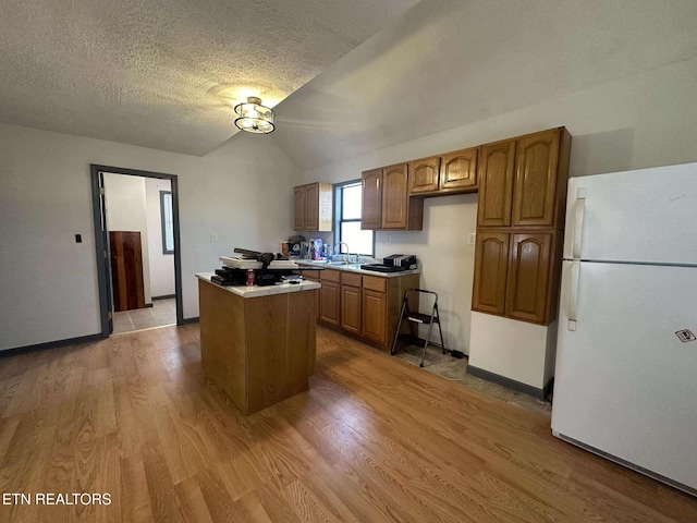 kitchen featuring a center island, light hardwood / wood-style flooring, white fridge, and vaulted ceiling