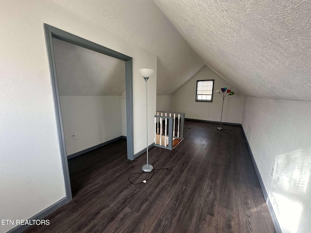 bonus room with a textured ceiling, vaulted ceiling, and dark wood-type flooring