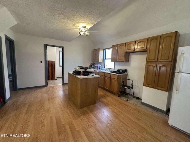 kitchen featuring a center island, lofted ceiling, white refrigerator, light hardwood / wood-style flooring, and a textured ceiling