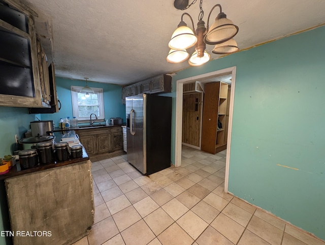 kitchen featuring sink, stainless steel fridge with ice dispenser, a chandelier, a textured ceiling, and light tile patterned floors