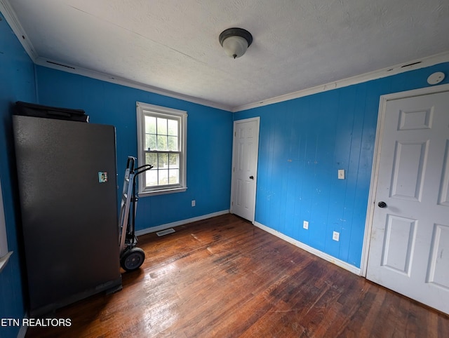 unfurnished bedroom featuring a textured ceiling, ornamental molding, and dark wood-type flooring