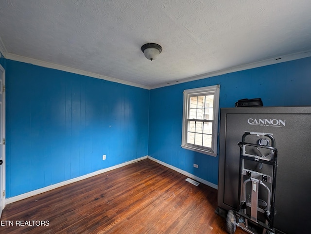 empty room with a textured ceiling, dark hardwood / wood-style floors, and ornamental molding