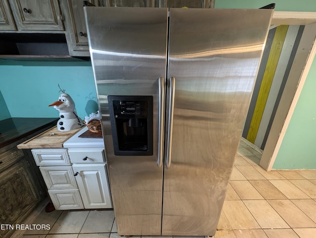 kitchen featuring white cabinets, stainless steel fridge, and light tile patterned floors