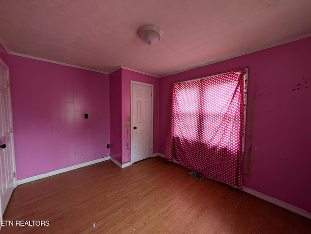 spare room featuring hardwood / wood-style floors and crown molding