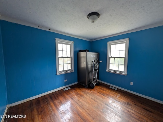 unfurnished bedroom featuring multiple windows, crown molding, dark hardwood / wood-style flooring, and a textured ceiling