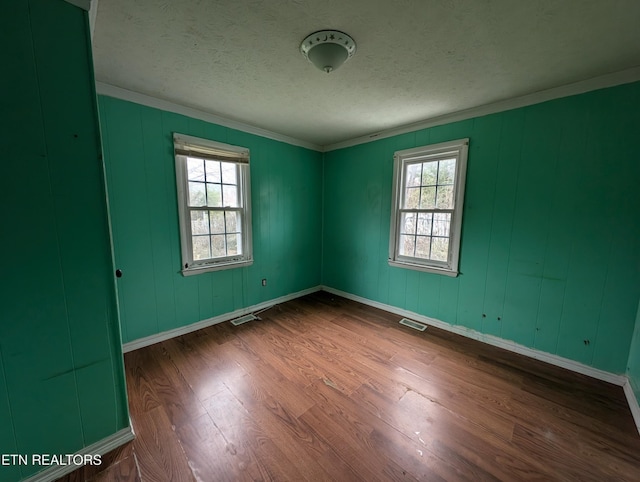 unfurnished room featuring a textured ceiling, wood-type flooring, and crown molding