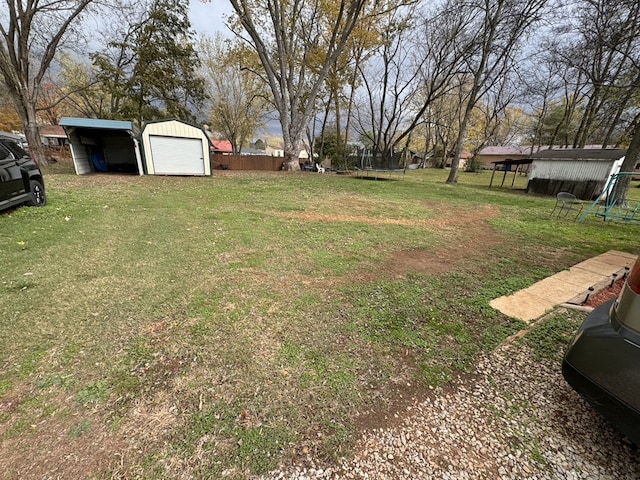 view of yard featuring a garage, an outdoor structure, and a carport