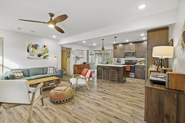 living room with ceiling fan and light hardwood / wood-style flooring